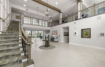 A large living room with a staircase and a lobby with stairs
